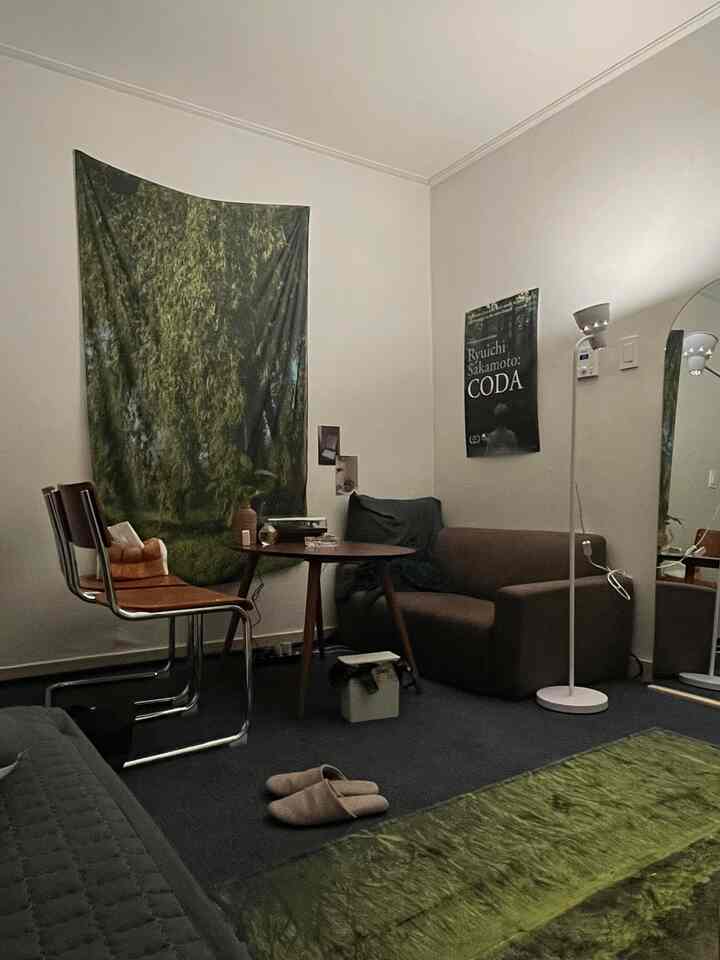 Cozy living room in green and brown tones featuring a sofa, round table, and floor lamp