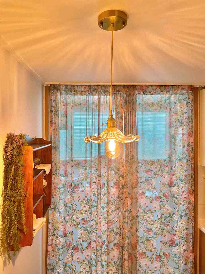 暖かいゴールドトーンとフローラルカーテンのあるヴィンテージ風キッチンスペース、居心地の良い明るい雰囲気