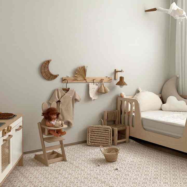 Beige and natural-toned kids' room featuring a baby crib, children's chair, and patterned rug in a warm atmosphere
