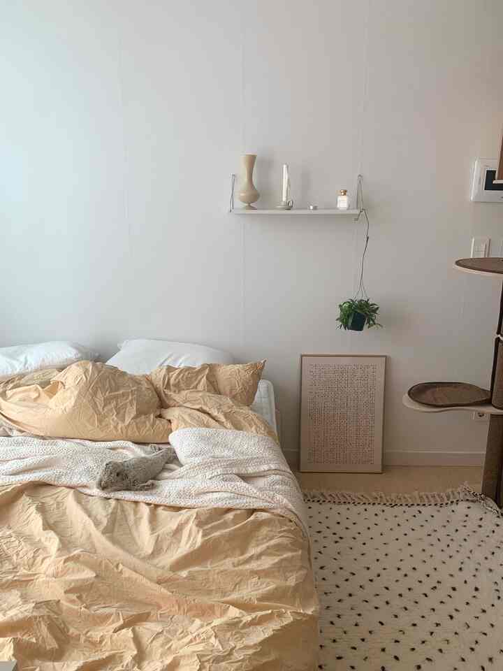 ナチュラルカラーと木目調の寝室、ベージュの寝具とキャットタワーが配置された雰囲気のある空間