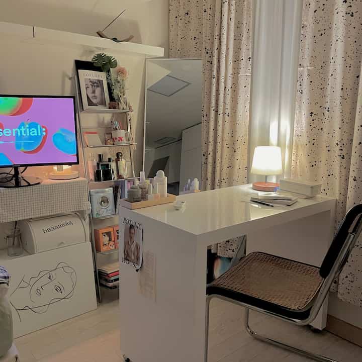 Cozy home office in white and beige tones with compact room layout featuring a desk, office chair, curtains, and a mirror