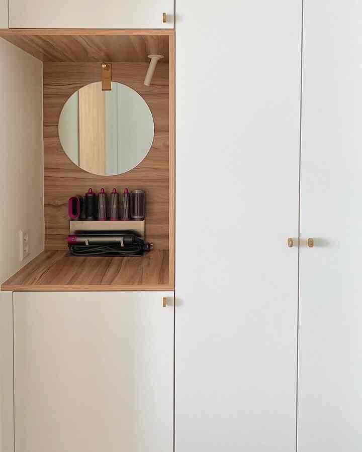 White and wood-toned walk-in closet featuring a neat vanity area with organized cabinets, creating a cozy atmosphere