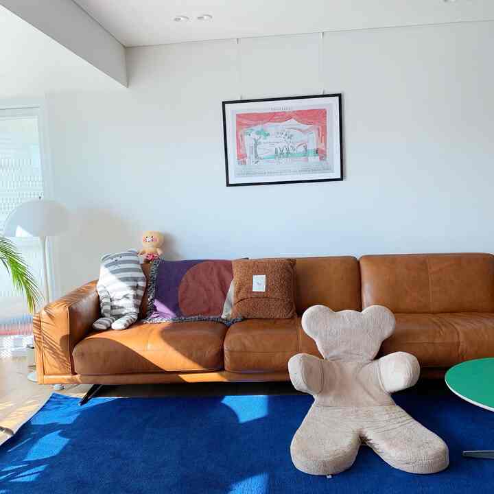 Bright and natural living room with brown leather sofa and beige bear-shaped armchair on navy rug