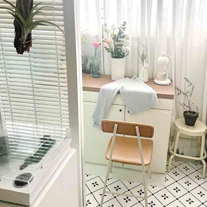White and wood tone veranda space featuring curtains and flower decor, creating a cozy small room ambiance