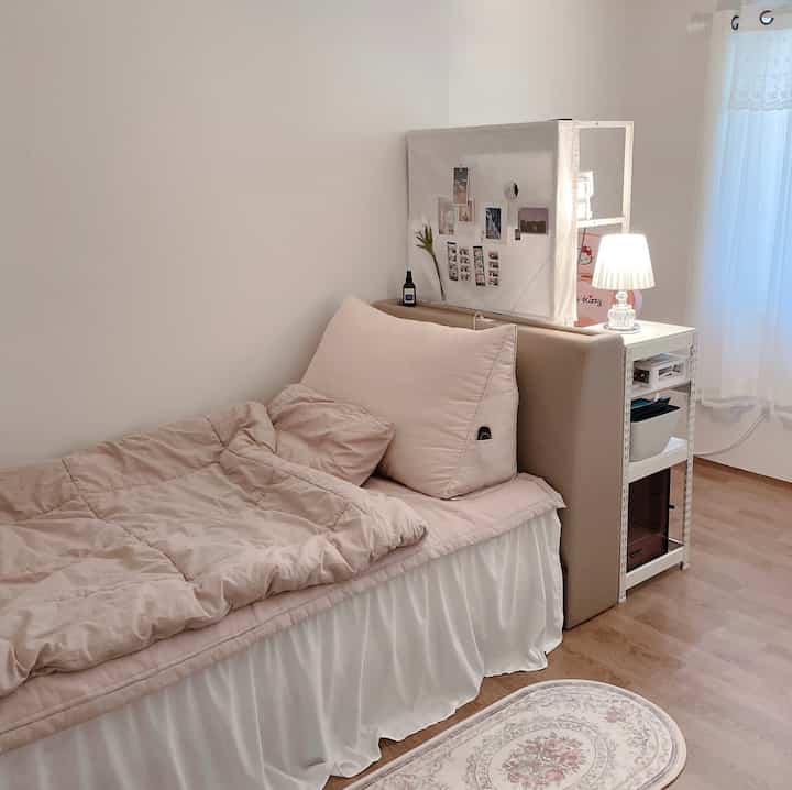 Cozy single bedroom in pink and white tones featuring a modern desk and soft lighting with a romantic atmosphere