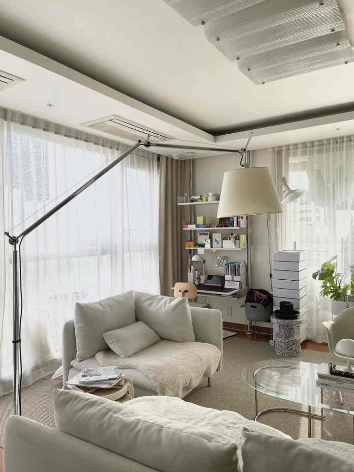 Bright white and natural tone living room featuring white sofas and large floor lamp, presenting a modern and clean atmosphere