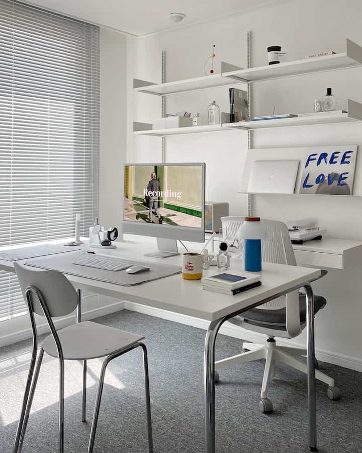 White-toned study space featuring a clean desk with computer and wall shelves in a modern home office