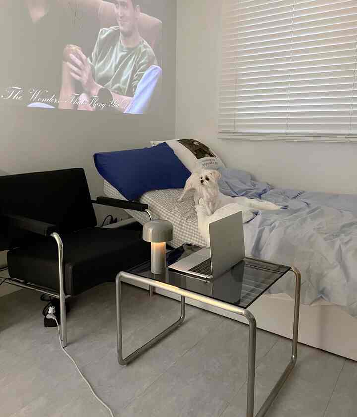 白と黒を基調にしたモダンな寝室、ブラインドとコンパクトな家具が配置された雰囲気のあるインテリア