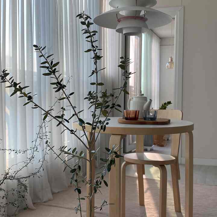 Natural tone dining room with light wood furniture and white sheer curtains creating a bright atmosphere