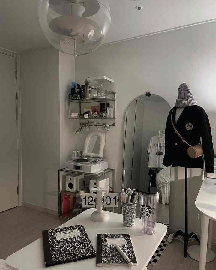 White and beige toned single household home office featuring mid-century modern furniture, a full-length mirror, and a flip desk clock in a stylish study room