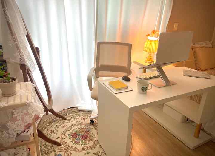 明るい白を基調としたワンルームのホームオフィス、整ったデスクとオフィスチェアが配置された居心地の良い空間