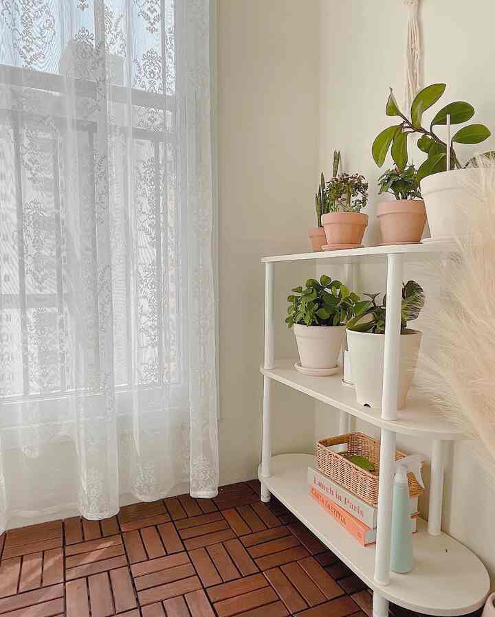 White and brown toned veranda featuring plant stands and lace curtains with a natural and cozy atmosphere