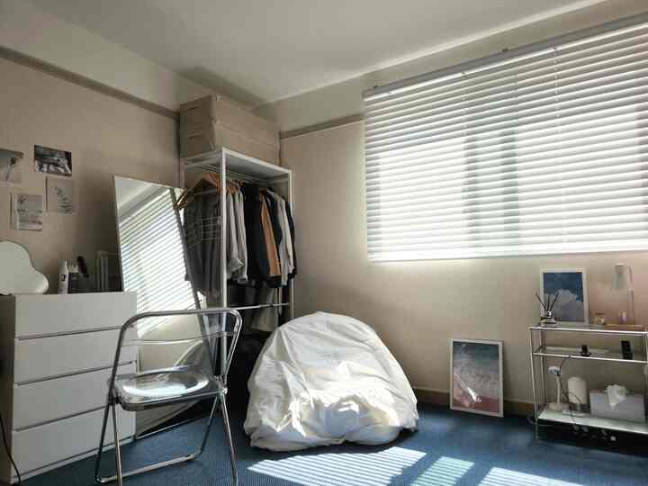 A white and monotone bedroom featuring a transparent chair and open wardrobe, creating a cozy atmosphere
