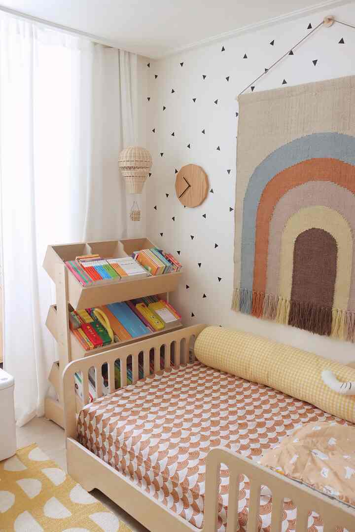 White and natural wood toned kids' room featuring a child’s bed, bookshelf, and playful decor for a warm atmosphere