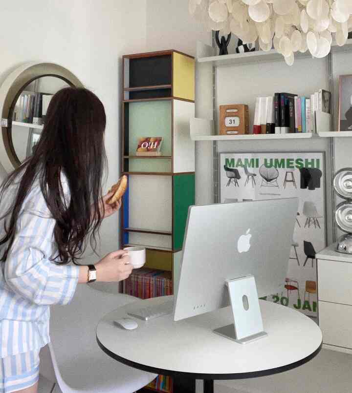 白い壁と丸いデスクを配したミッドセンチュリーモダンな書斎、カラーブロックの棚とコンピューターが置かれた雰囲気のあるホームオフィス