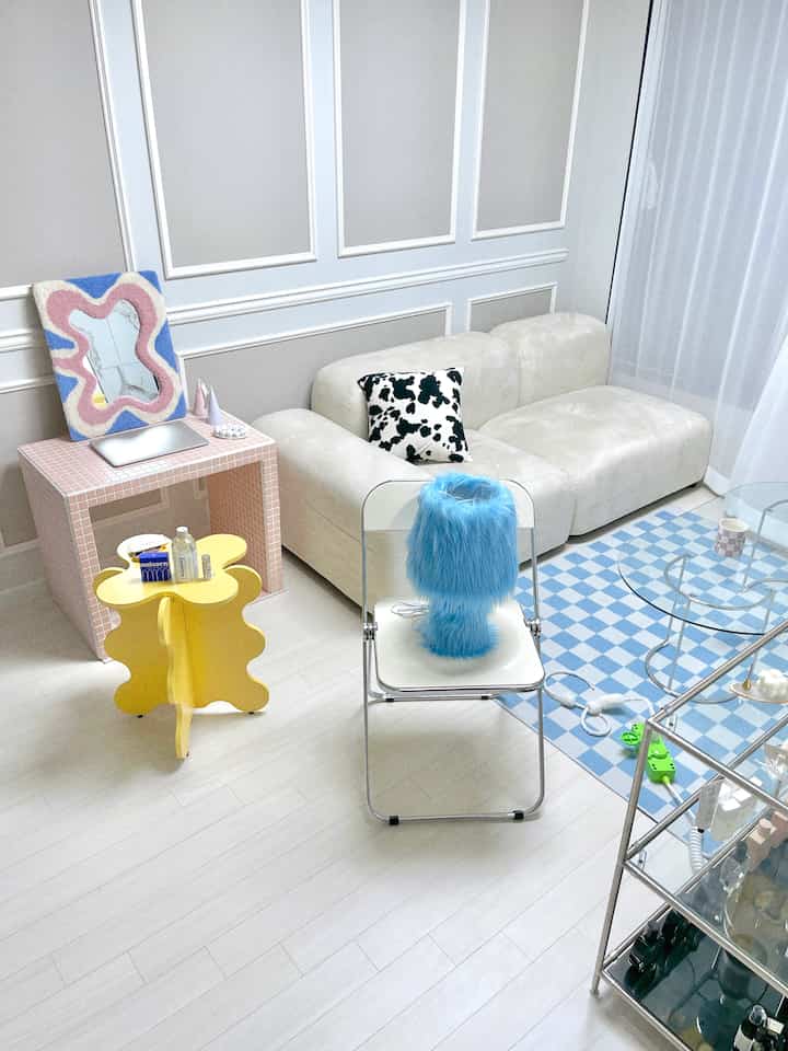 White and blue toned living room featuring Mid-Century Modern sofa, checkered rug, and a distinctive fluffy blue table lamp on a white chair