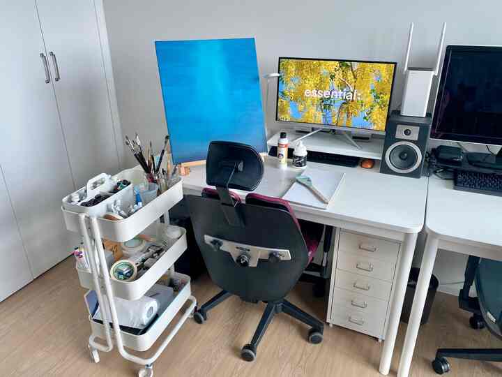 White and wood tone study space featuring white desks, drawer unit, monitor stands, and trolley in a compact home office setup