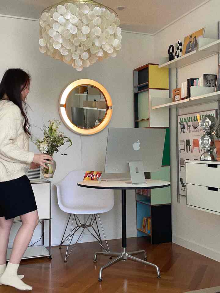 ホワイトと木目調の温かみのあるホームオフィス書斎、ミッドセンチュリーモダン家具と壁掛け棚、丸い鏡が配置された雰囲気のあるインテリア