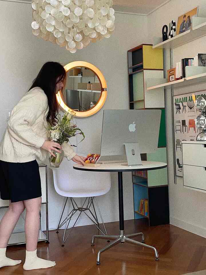 White and wood-tone studio home office featuring a round table, Eames chair, and Apple iMac in a minimal and natural workspace