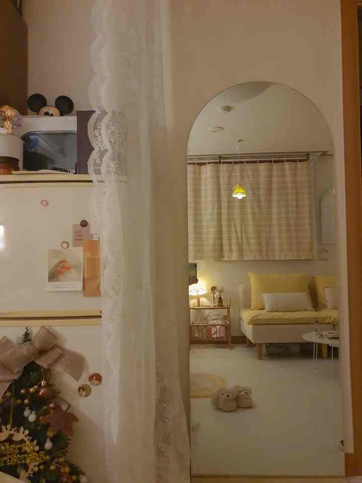 ナチュラルで温かみのある黄色いカーテンとソファのリビング、ラタンのサイドテーブルとフレームレスのラウンドミラーが空間を広く見せる雰囲気のあるインテリア