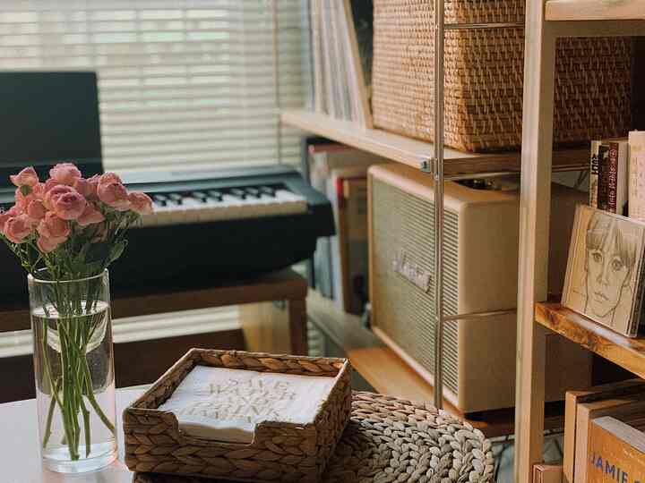 Warm brown wood shelves with rattan accessories and a keyboard piano in a cozy home cafe space
