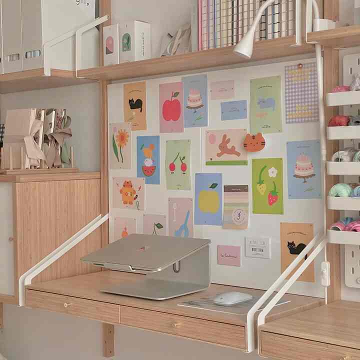 Natural color and white toned home office space featuring wooden desk and colorful postcards on wall creating cozy work area