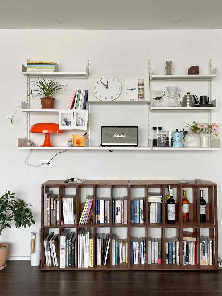 White-walled modern living room with shelves and brown wooden bookshelf showcasing a natural home cafe setup