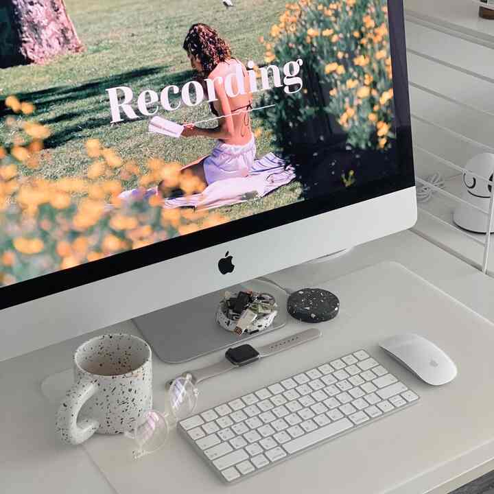 ホワイトトーンのリビングホームオフィス、iMacとキーボード、マグカップが整然と配置されたシンプルなインテリア