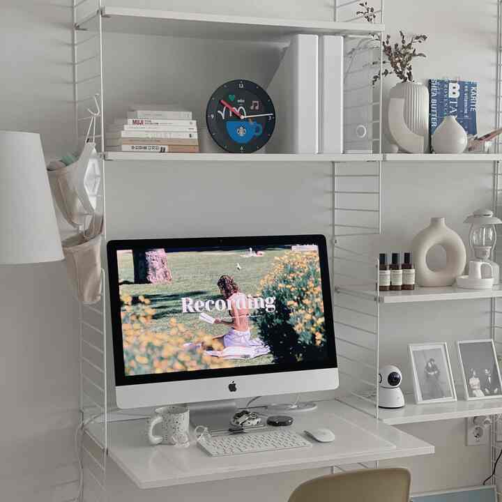White-toned home office featuring a central iMac and desk with a clean modern interior design