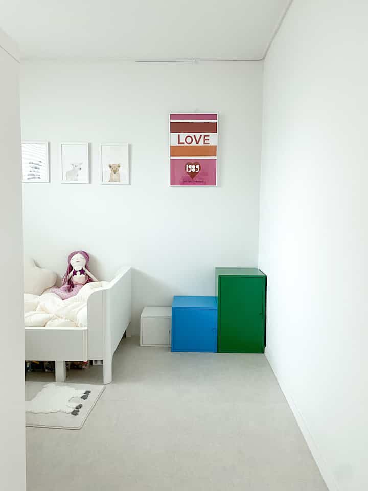 白を基調とした子供部屋、カラフルな収納棚とベッドが配置されたシンプルで落ち着いた雰囲気のインテリア