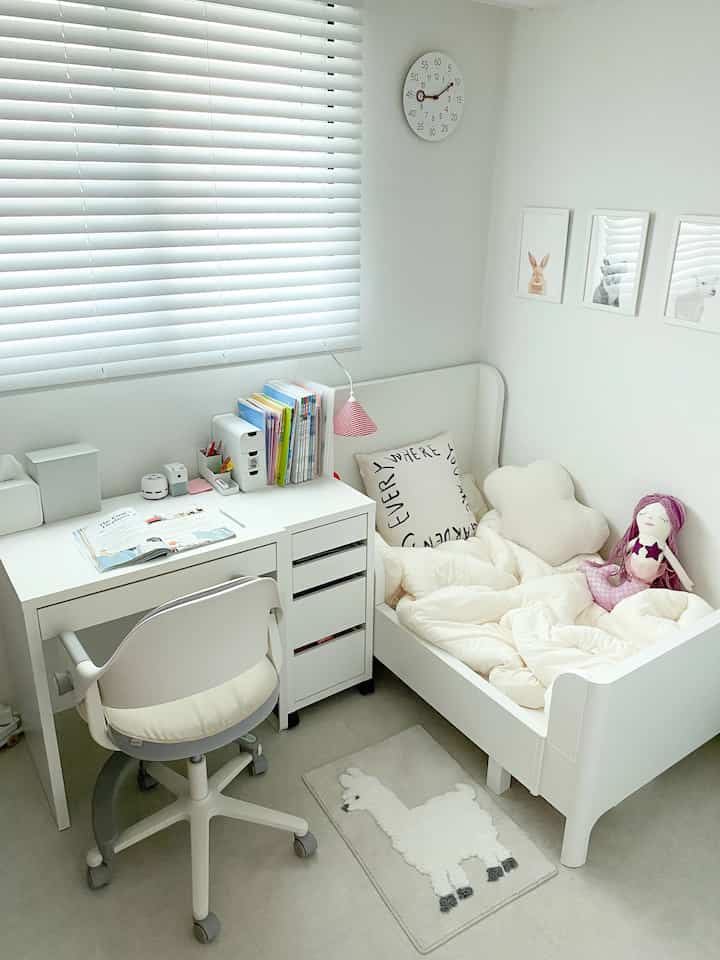 Bright white-toned kids' room featuring a desk and child-sized bed in a clean, minimal style
