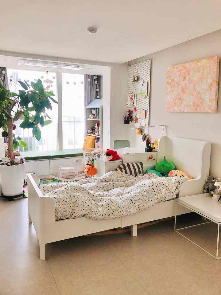 明るいホワイトトーンの子供部屋、子供用ベッドと机、おもちゃ収納、窓辺のベンチが配置された清潔でミニマルなインテリア