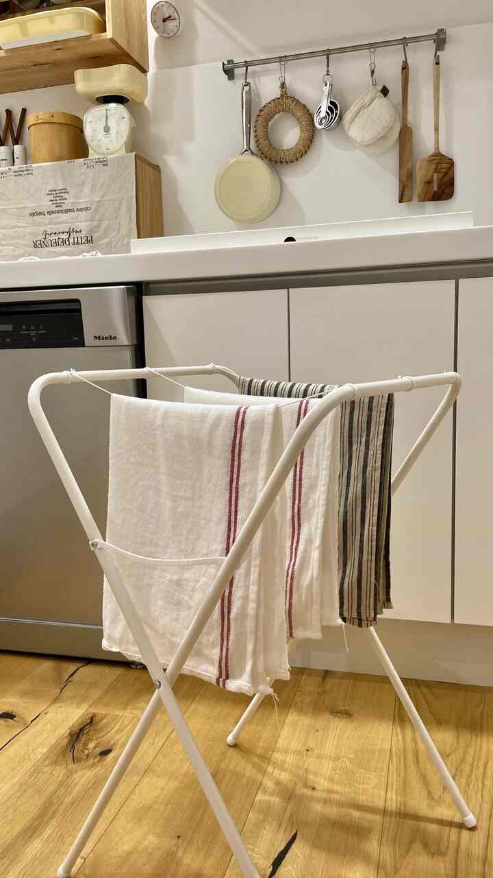 White and wood tone kitchen space featuring a drying rack with kitchen towels draped, presenting a clean look