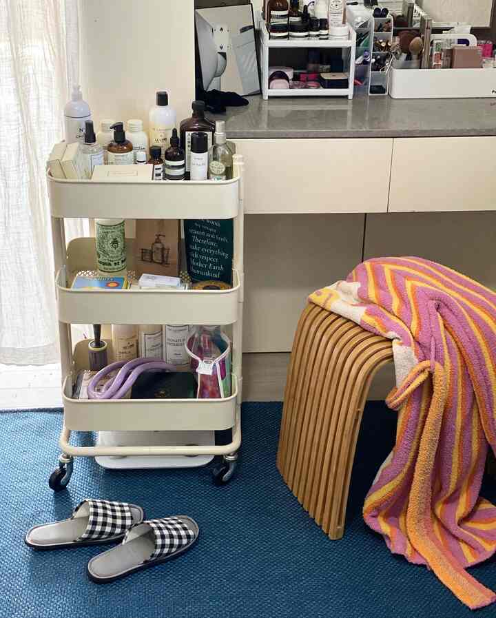 Blue and white toned walk-in closet powder room featuring cream trolley and wooden stool creating a neat organized space