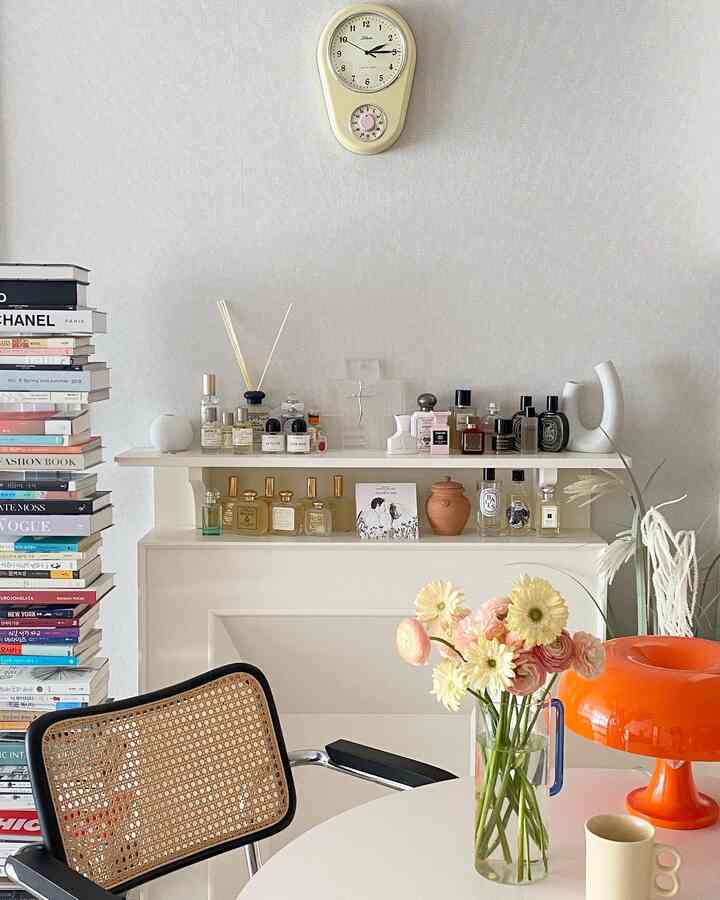 明るいナチュラルトーンのリビングとダイニングルーム、ヴィンテージ時計とラタンのアームチェア、花瓶が置かれた雰囲気のある空間