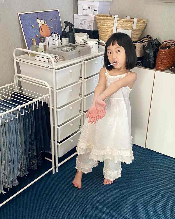 White drawer units and blue rug in a walk-in closet, featuring a child at the center in an organized space