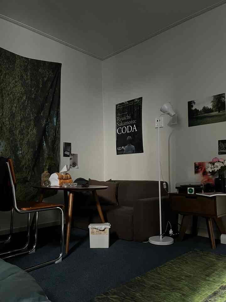 Brown and green toned single household living room featuring sofa, round table, and floor lamp with cozy atmosphere