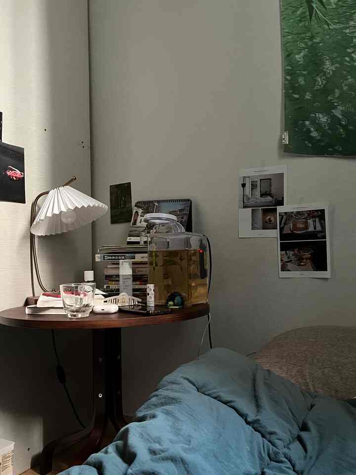 ブルーの寝具と木製のサイドテーブルが配置された、一人暮らし向けの居心地の良い寝室