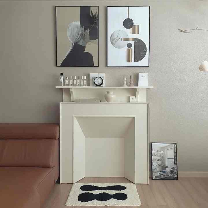 Modern living room with ivory fireplace and brown sofa, featuring simple posters and a rug creating a cozy atmosphere