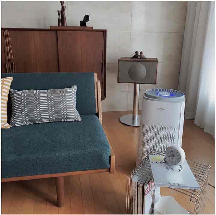 ナチュラルモダン調のリビング、ブルーのソファと木製家具、白い空気清浄機と遮光カーテンが配置された落ち着いた雰囲気の空間