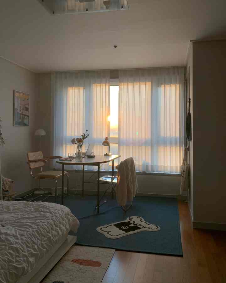 暖かい日差しが差し込む青いラグと木製家具がある6畳のワンルーム寝室の雰囲気あるインテリア