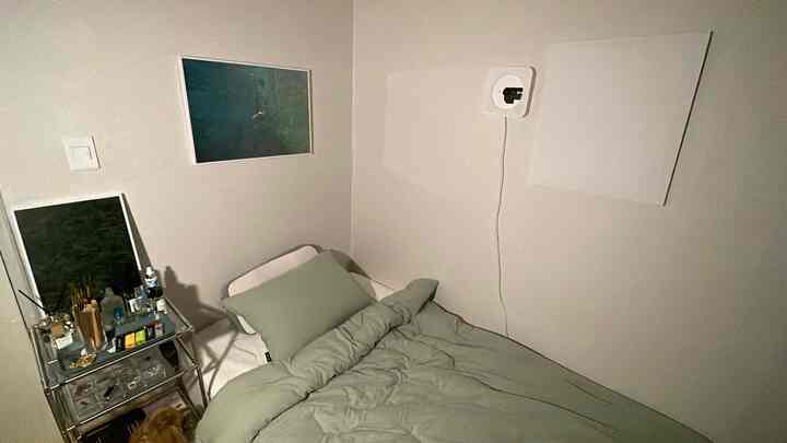 Beige-toned single household bedroom featuring a bed with green bedding and wall sconce, creating a cozy atmosphere