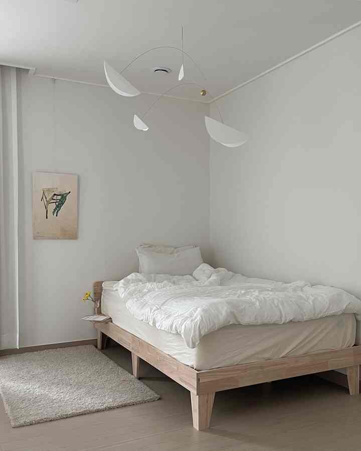 A natural color and wood tone bedroom with a wooden bed frame and white bedding creating a simple and calm space