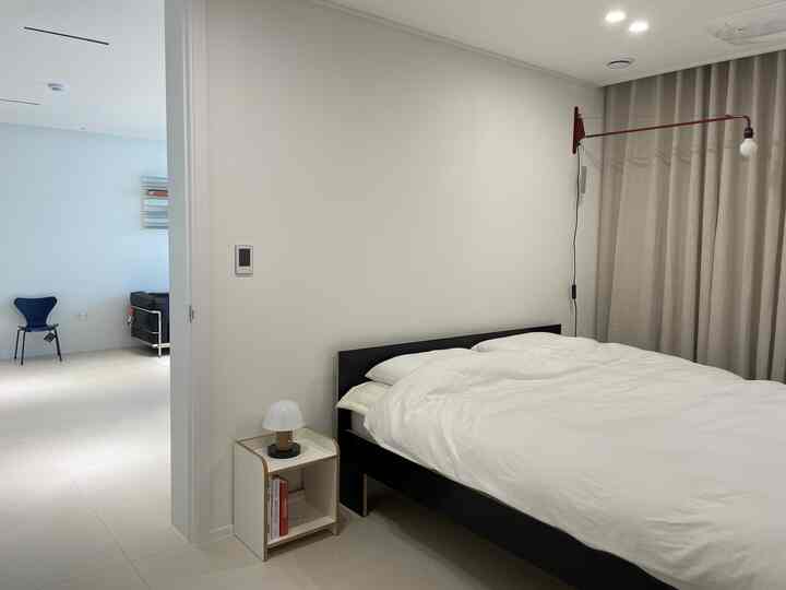 White and black toned bedroom featuring black bed frame, simple nightstand, and bright minimal atmosphere
