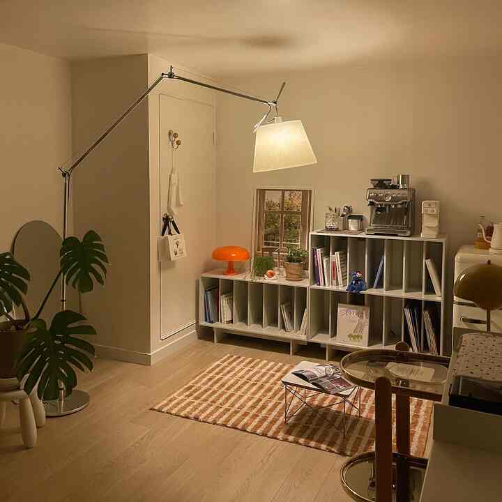 A cozy workspace home cafe in white and brown tones featuring Artemide lighting, coffee machine, and bookshelf