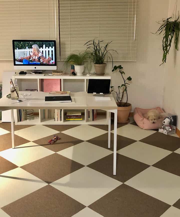 White and brown toned compact home office featuring desk, computer, plants with a simple atmosphere