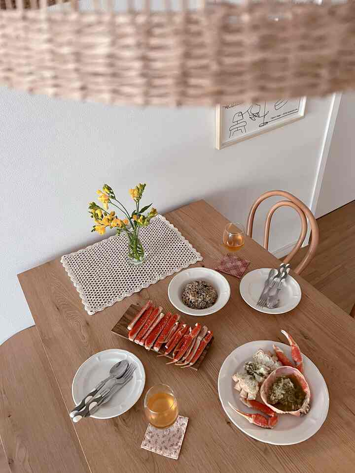 Beige and wood tone dining room featuring a wooden table with a vase, wine glasses, and a simple meal, creating a cozy atmosphere