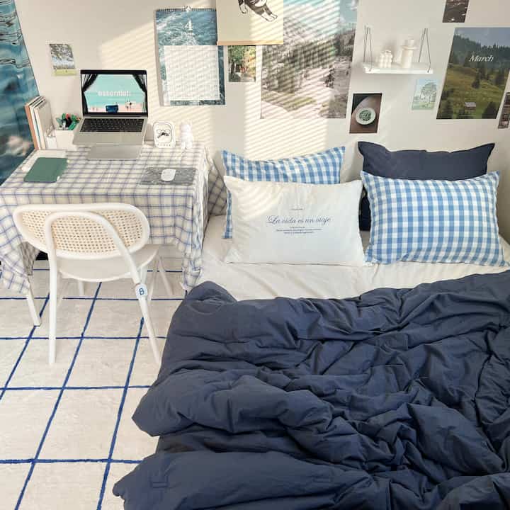 ブルーとホワイトの色調の寝室、チェックの枕とテーブルクロスが配置されたモダンでコンパクトな空間