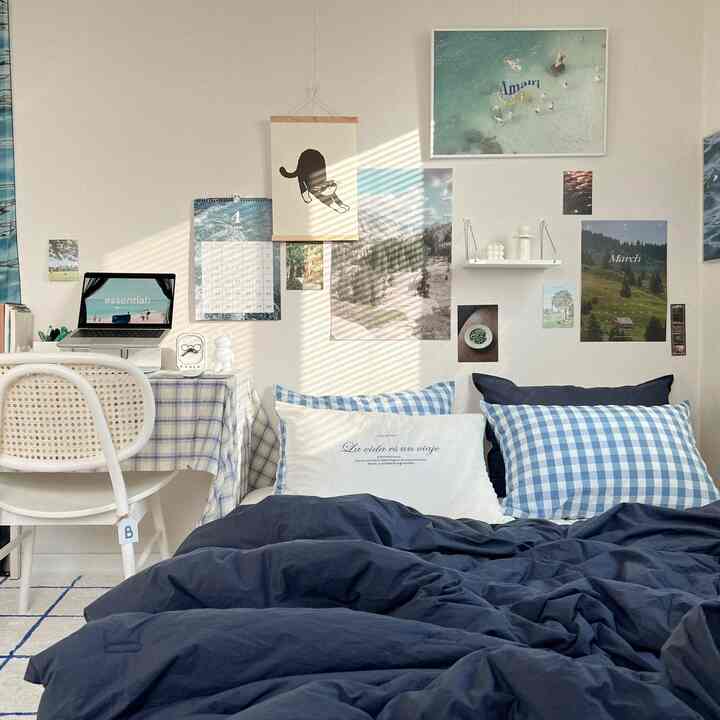 Blue and white toned bedroom featuring a bed, desk, and posters creating a cozy and simple single household space