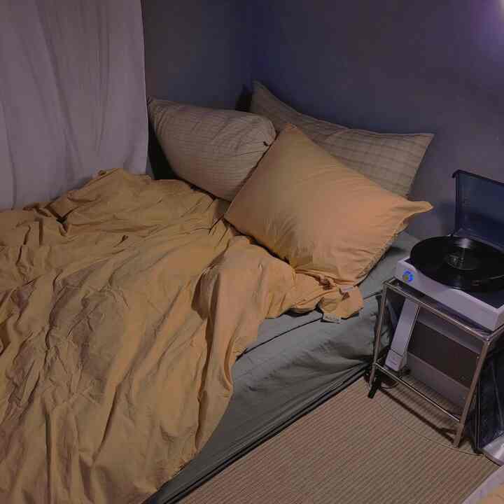 Yellow bedding and pillows in a gray-toned bedroom, cozy space featuring a vintage record player